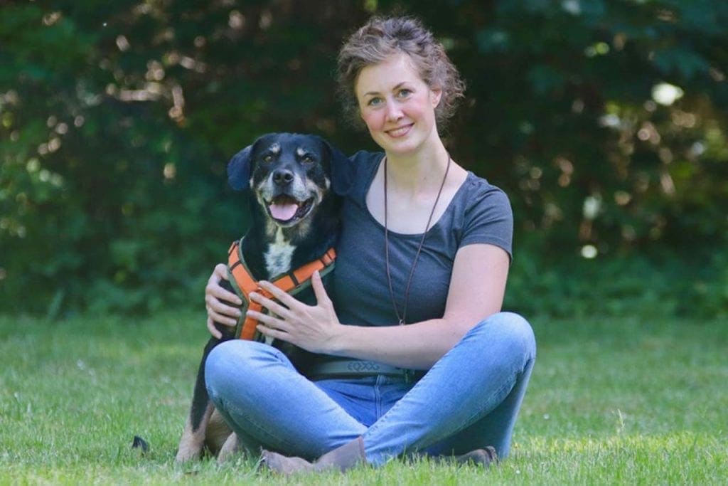 Dr. Lara Steinhoff sitzt mit ihrem Bracken Mix auf einer Wiese